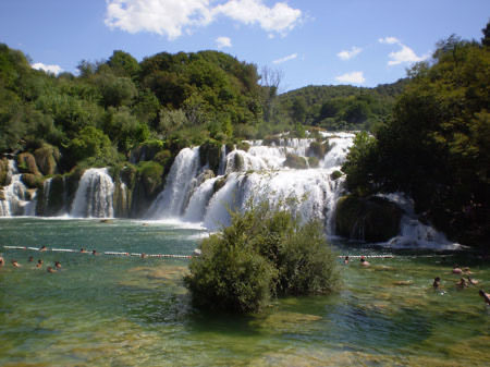 Breite, flache Wasserfälle der Krka zwischen dichtem Grün.